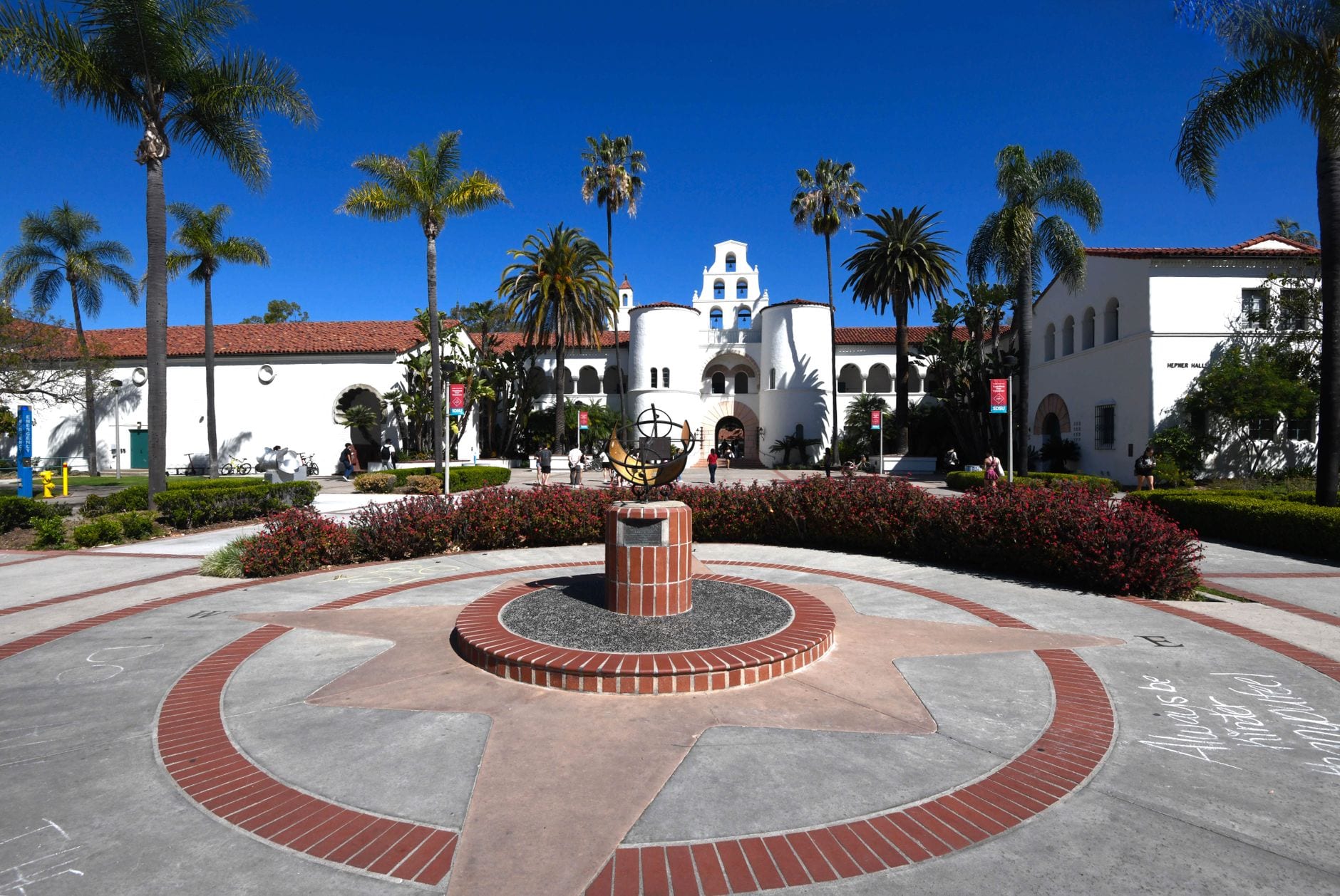 Sunny day at a historic university with palm trees and compass in the courtyard.